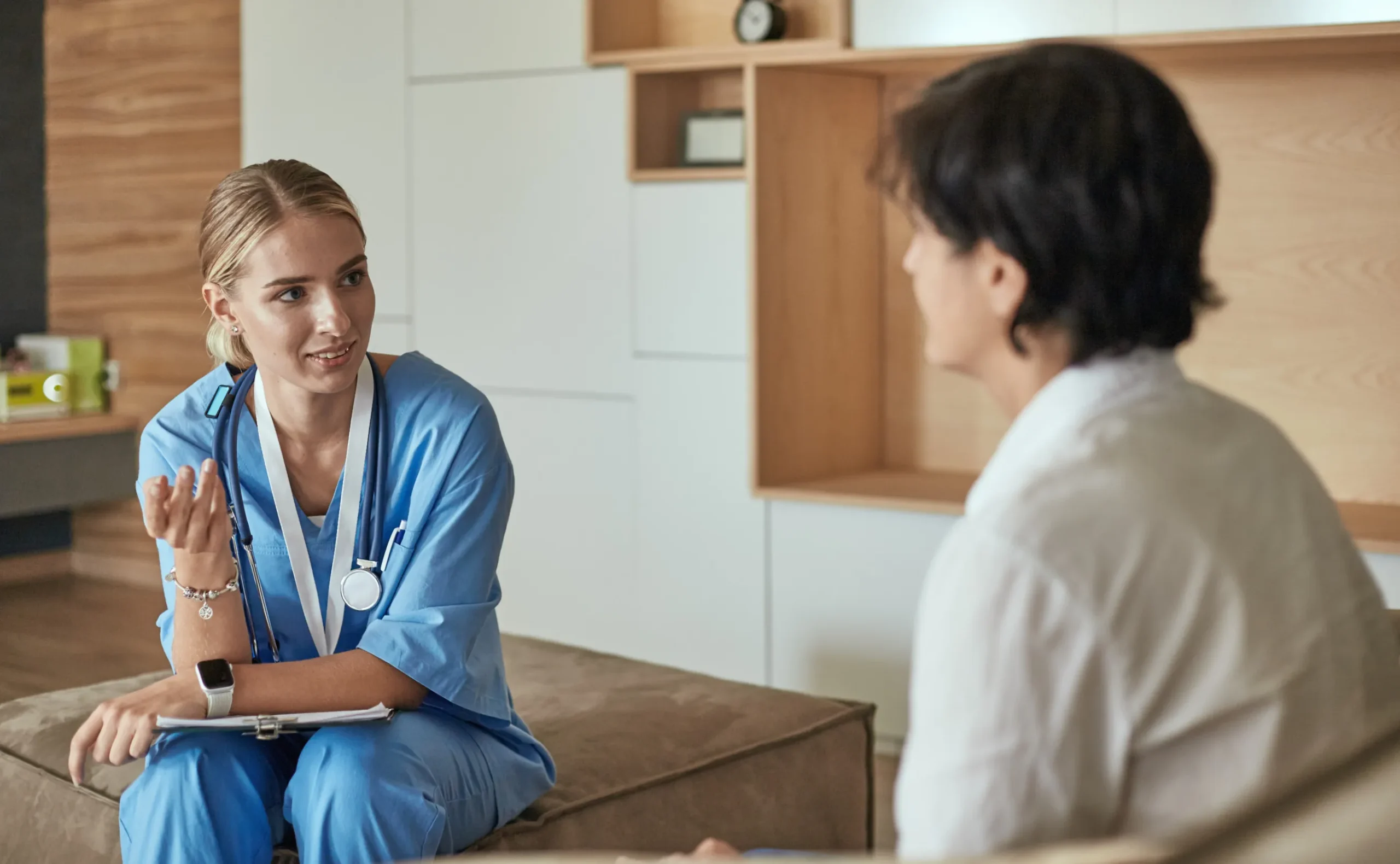 a woman in blue scrubs talking to a man - Mental health