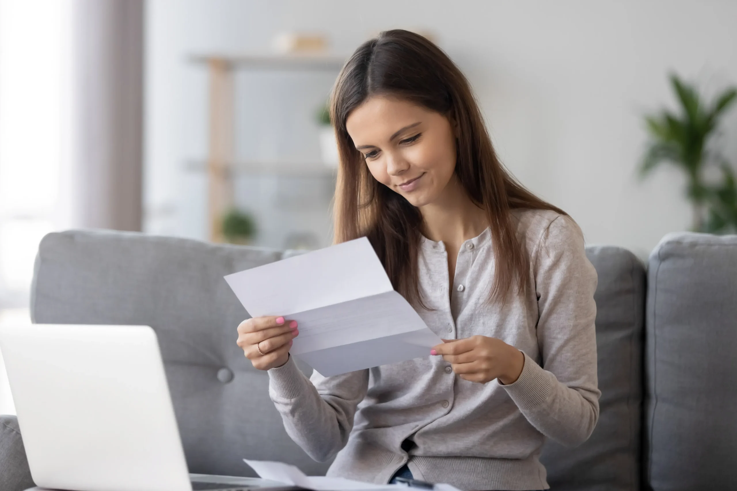 a woman sitting on a couch reading a paper