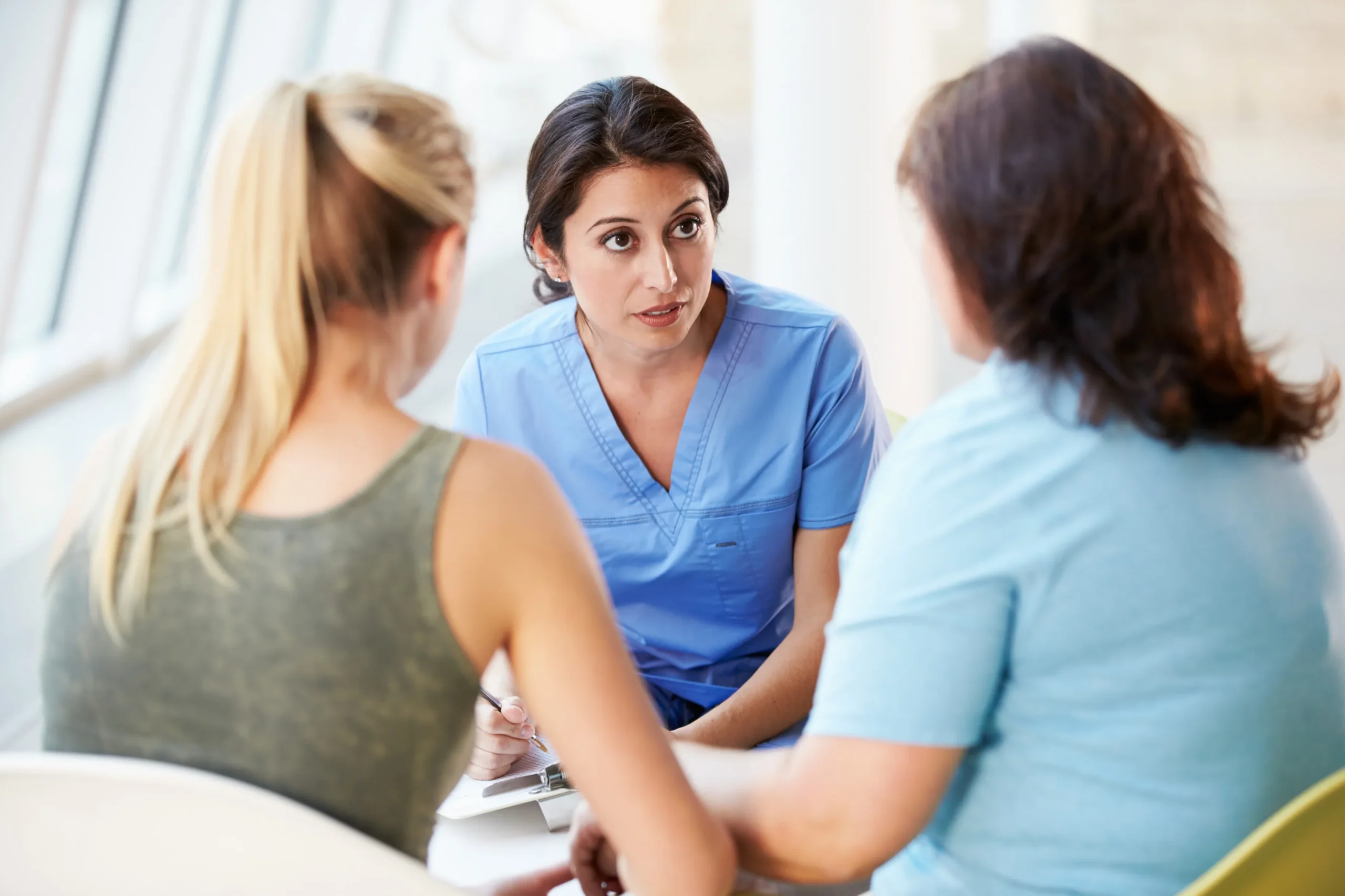 a woman in blue scrubs talking to a group of women