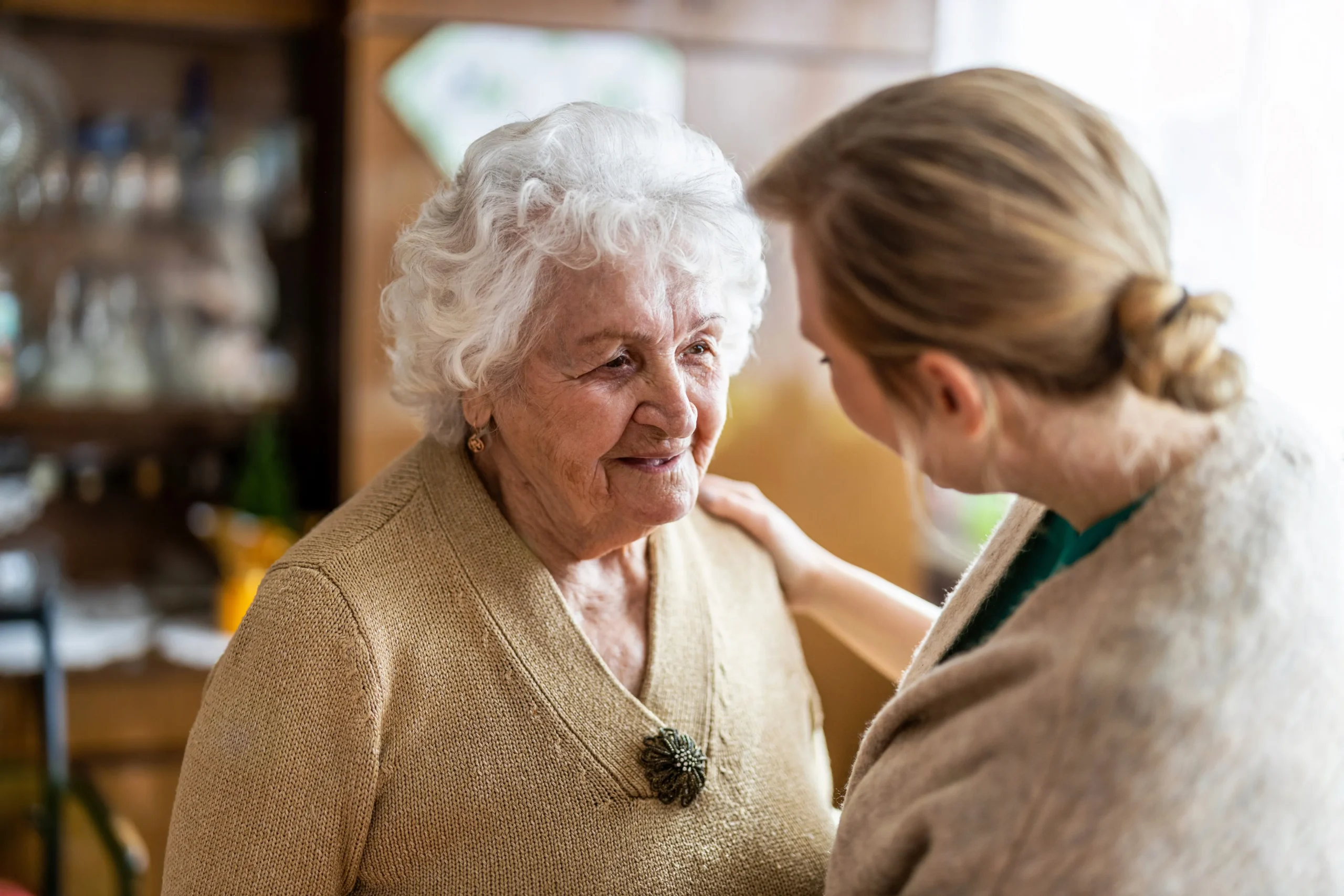 a woman looking at an older woman - Dementia Care cover