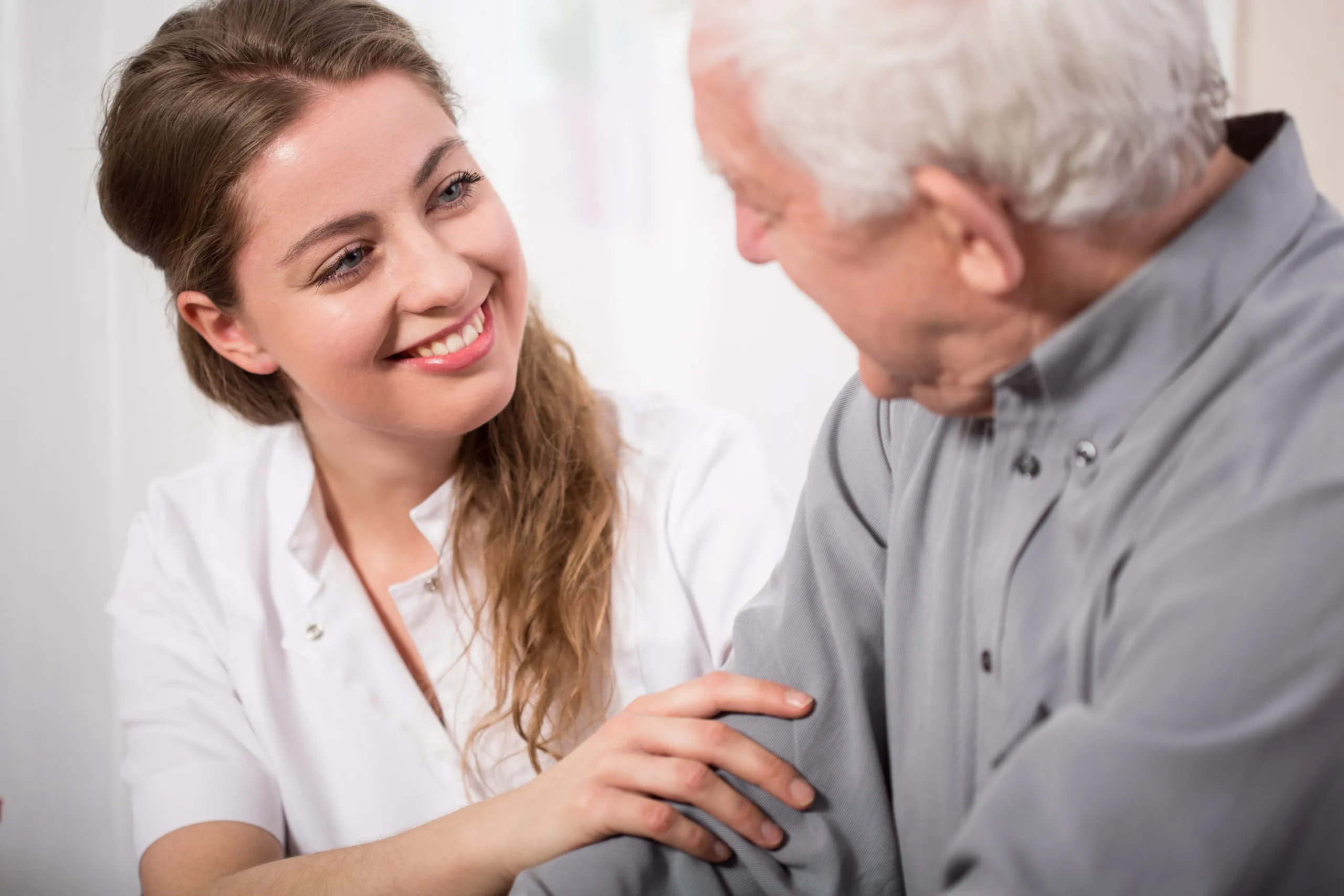 a woman smiling at an old man - Elderly Care Services cover