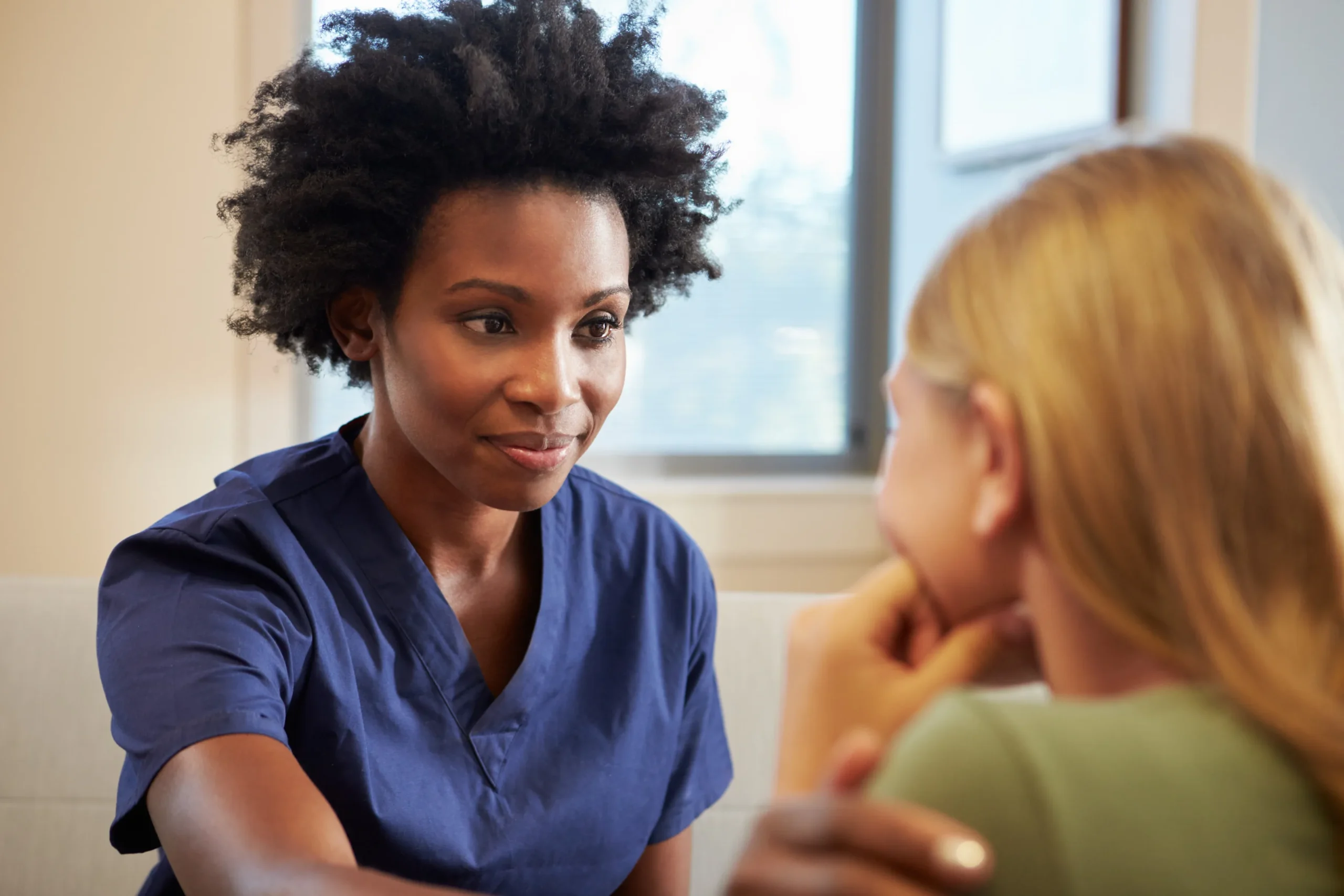 a woman in blue scrubs talking to a woman