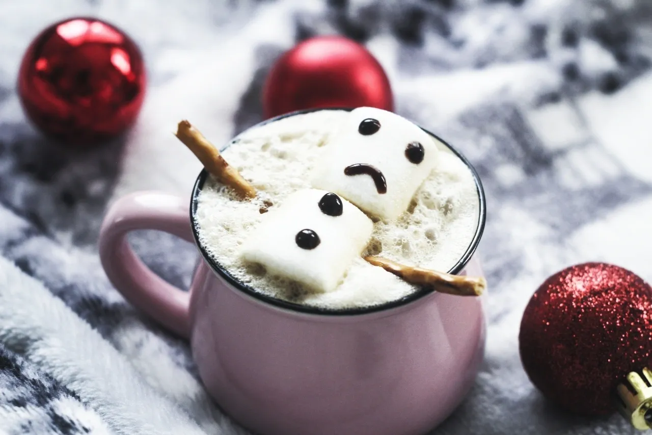 a mug of hot chocolate with marshmallows and pretzels - Loneliness during holidays cover